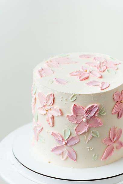 Birthday, wedding or anniversary cake with white cream cheese frosting and decorated with pink cream flower petals. White background