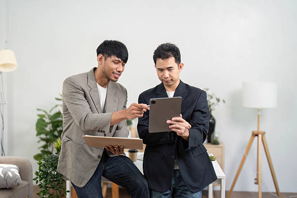 istock Business Discussion and Collaboration. Two professionals engaged in a productive meeting, analyzing data on a tablet. 2213860136