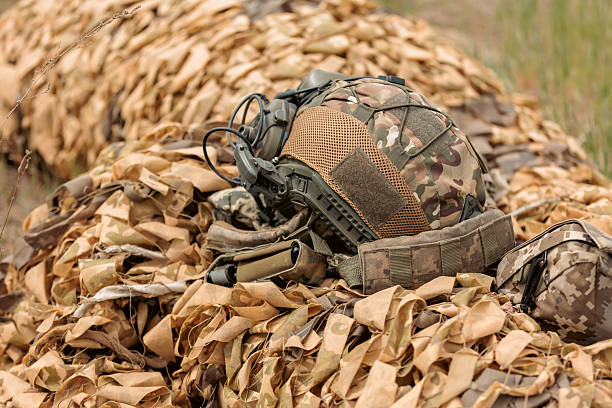 istock Military helmet lies on camouflage net 2213860848
