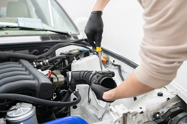 istock A technician in gloves works diligently with a screwdriver on an engine part in a well-lit automotive repair shop. 2213864208