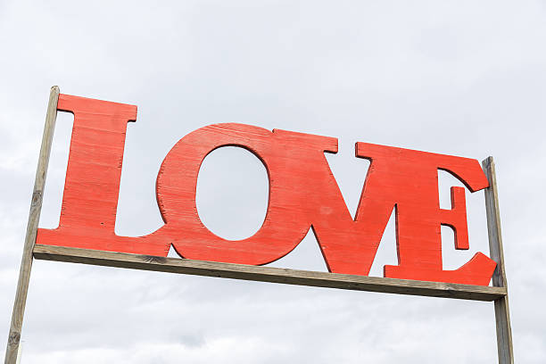 Red love sign on wooden frame against cloudy sky background, lifestyle