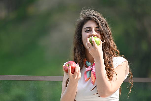 close up of a young woman with towel wrapped around her hair holding a red apple in her hand ready to eat