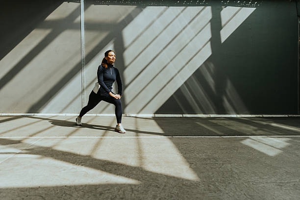istock Dynamic stretching routine in a sunlit urban gym with striking shadow patterns on the floor 2213868311