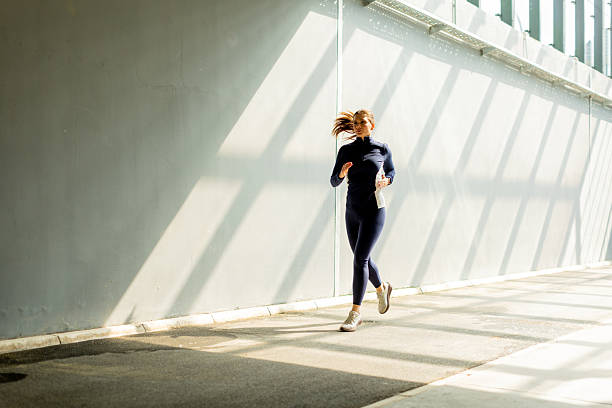 istock Jogger dashes along a sunlit pathway, shadows stretching across the ground in a bustling urban setting 2213868427