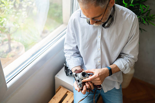istock Man examining a vintage camera indoors near a window 2213869261