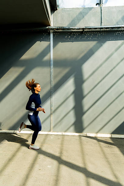 istock Dynamic urban runner embracing morning sunlight through geometric shadows in a modern space 2213869575