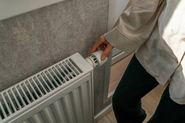 istock A person is adjusting the power settings on a radiator thermostat, ensuring optimal heating for comfort in a domestic environment 2213869924