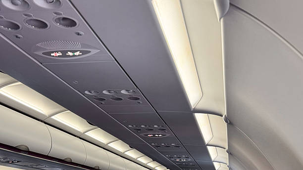 Interior view of airplane cabin ceiling with overhead aisle lights and control panels during flight providing modern aviation ambiance
