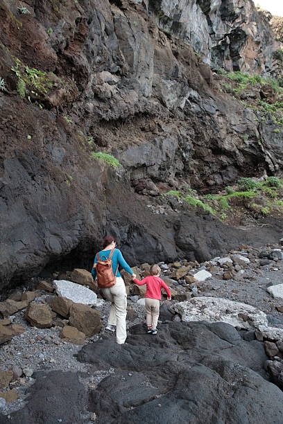 istock Tourists walking on rocky path near volcanic cliff 2213872037