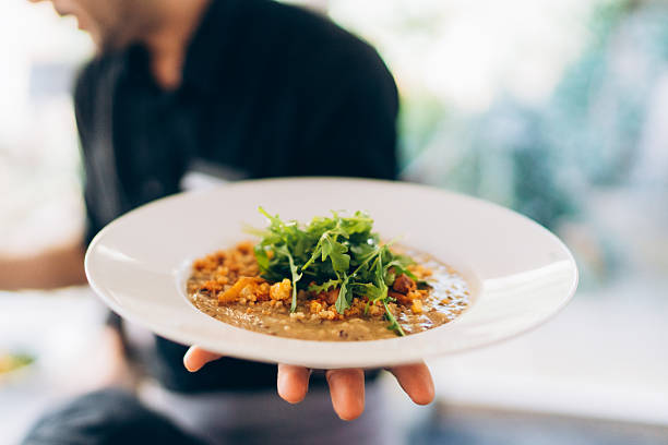 istock Chef serves a gourmet dish with fresh arugula and savory ingredients in a vibrant dining setting 2213873158