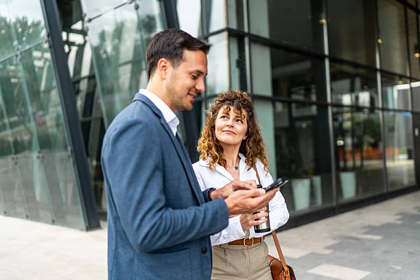 istock Businesspeople using smartphone and discussing outside office building 2213873573