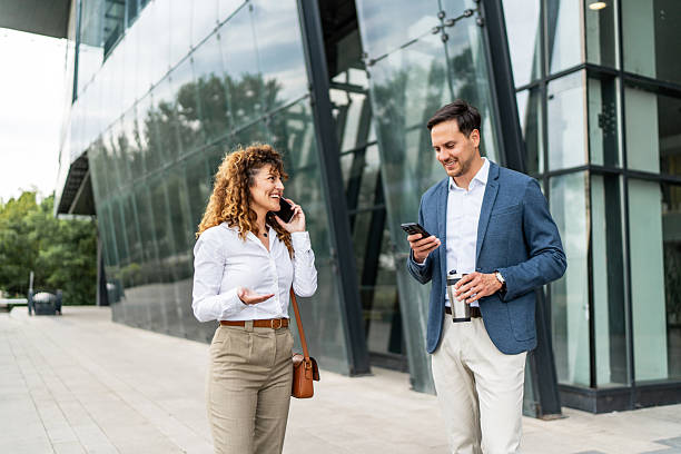 istock Businesspeople walking and using smartphones outside office building 2213873994