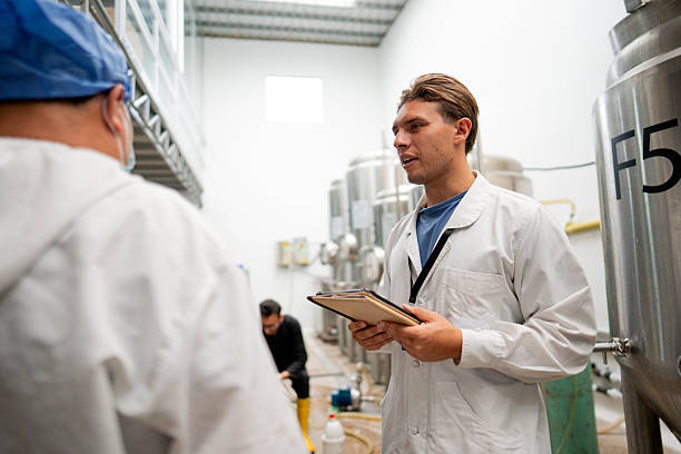 istock Young man using digital tablet while talking with coworkers in a brewery 2213876622