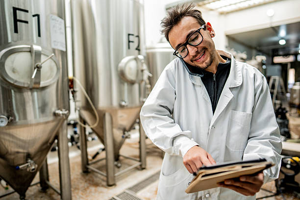 istock Young man using digital tablet and talking on mobile phone in a brewery 2213876733