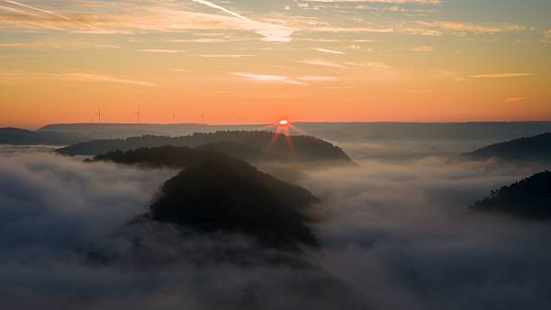 istock Sunrise over misty hills with wind turbines 2213877096