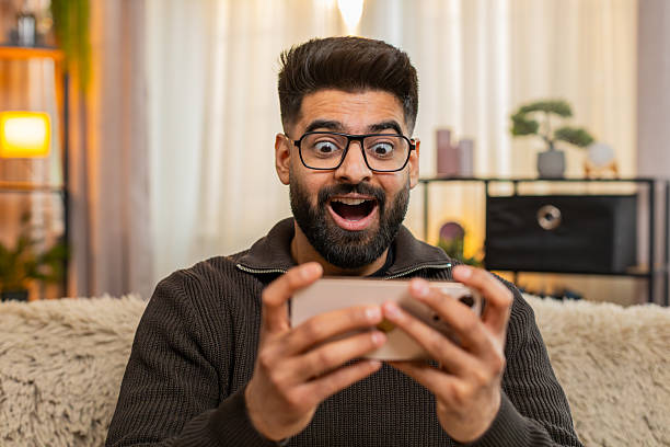 istock Indian man happily celebrates victory win at home using smartphone, joyful expression 2213877462