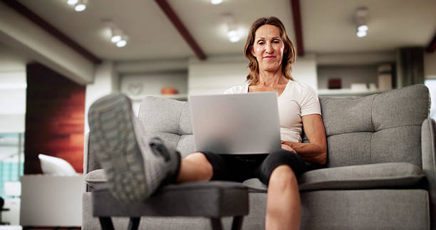 Smiling Woman On Crutches Happily Working On Laptop