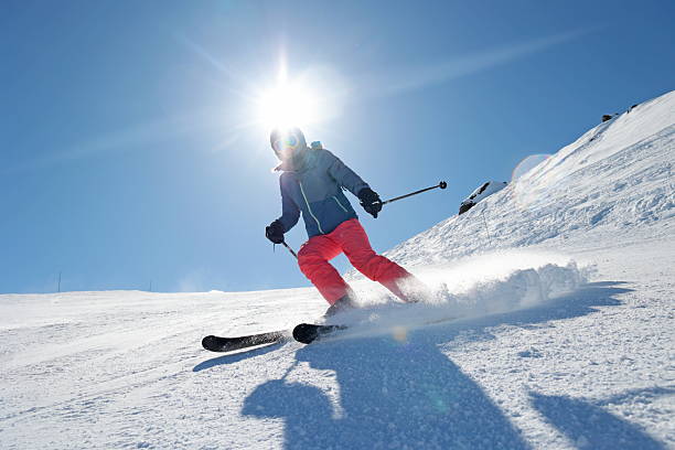Woman skis down ski slope on sunny day