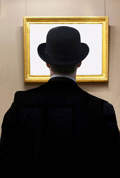 istock Man wearing bowler hat looking at blank picture frame on wall 2213881617