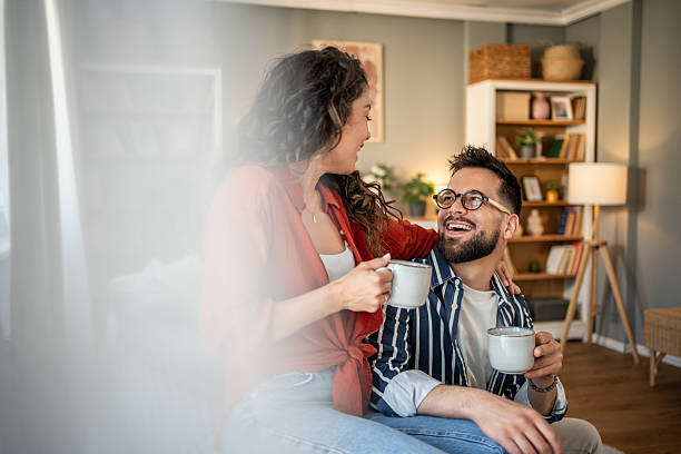 istock Young couple relaxing on sofa, drinking coffee and sharing a laugh 2213882386
