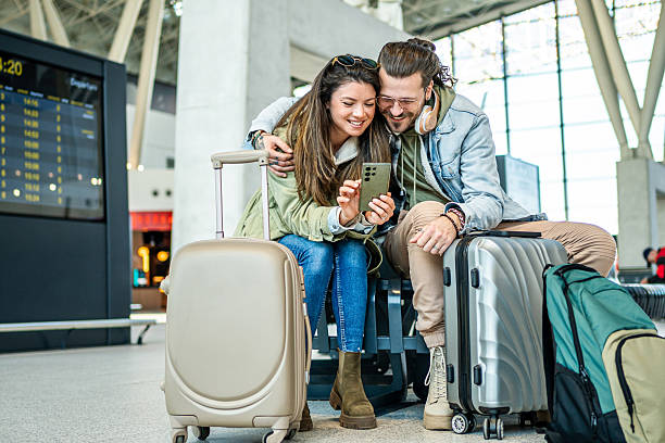 istock Young couple using smartphone at the airport while waiting for their flight 2213882396