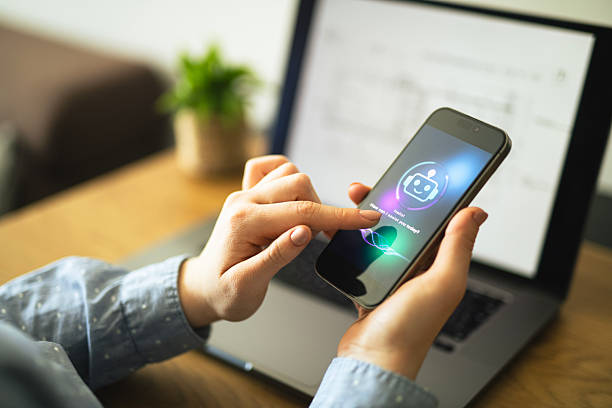 istock Businesswoman using AI chatbot app on smartphone to assist her while working on laptop. 2213882551
