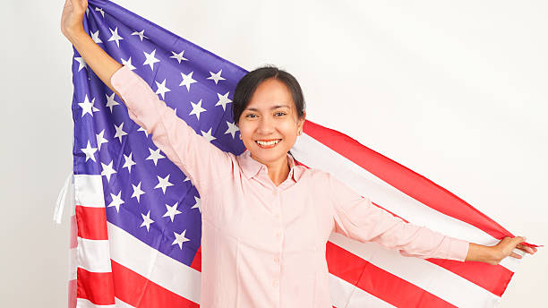 istock Woman smiling while raising American flag on white background 2213884531