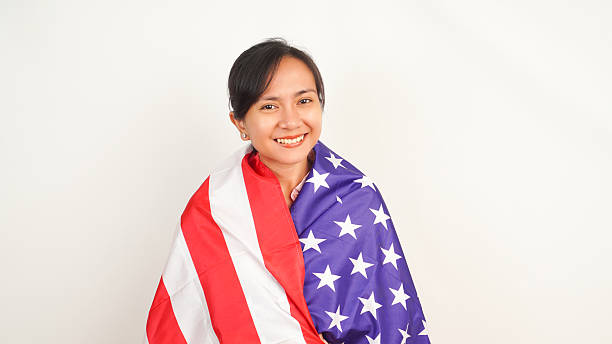 istock Happy female with USA flag around shoulders on white backdrop 2213884535