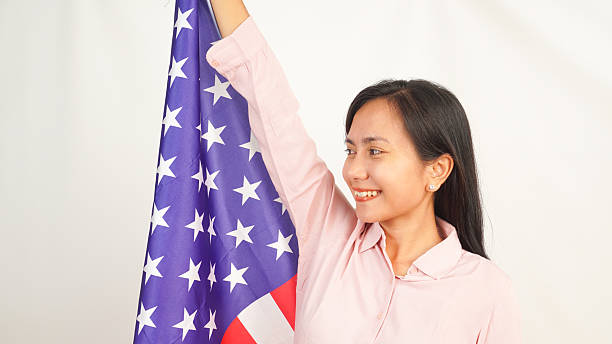 istock Woman proudly holding American flag while smiling on white background 2213884816