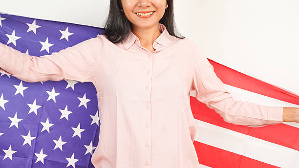 Woman smiling while waving large American flag on white background