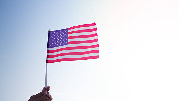 istock USA flag lifted by hand under sunny sky 2213885044