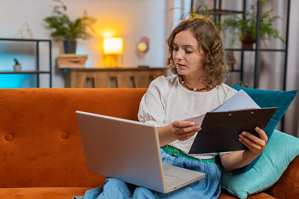 istock Woman accountant using laptop working with financial graph documents, reports of home income on sofa 2213886929