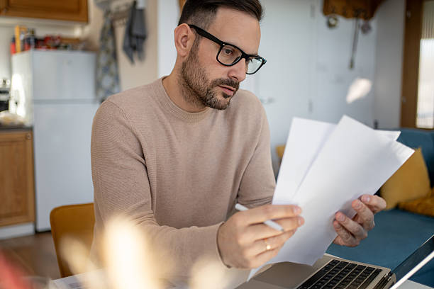 istock Focused man reviewing documents at home office desk 2213887414