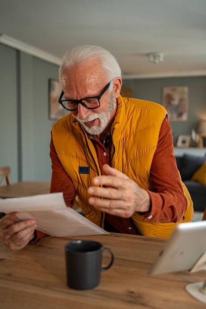 istock Senior man reading documents and having a video call at home 2213888464