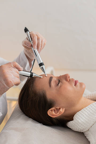 istock Beautician doctor makes woman micro currents face therapy using electrical impulses in spa salon 2213890079