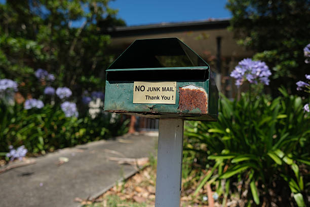 Old rusty mailbox green with no junk mail sign on a sunny day.