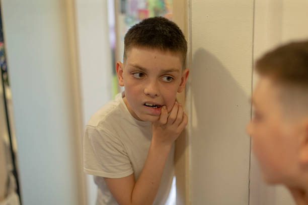 istock A curious young boy thoughtfully gazes at his own reflection in the mirror 2213893388