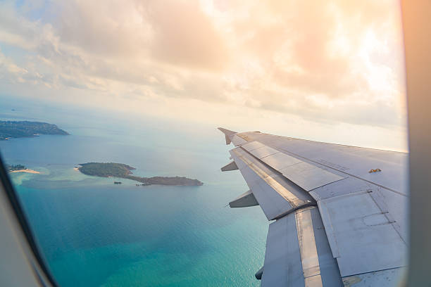 istock Breathtaking aerial view from an airplane soaring above tranquil blue waters and distant islands at sunset 2213894989