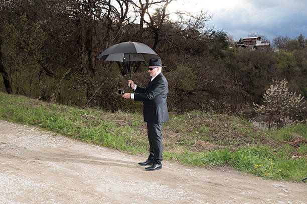 Englishman with bowler hat and umbrella  on the beach overlooking the sea and towards Europe.