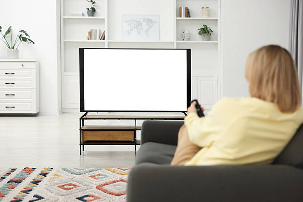 istock Woman watching TV on sofa at home, back view 2213901546