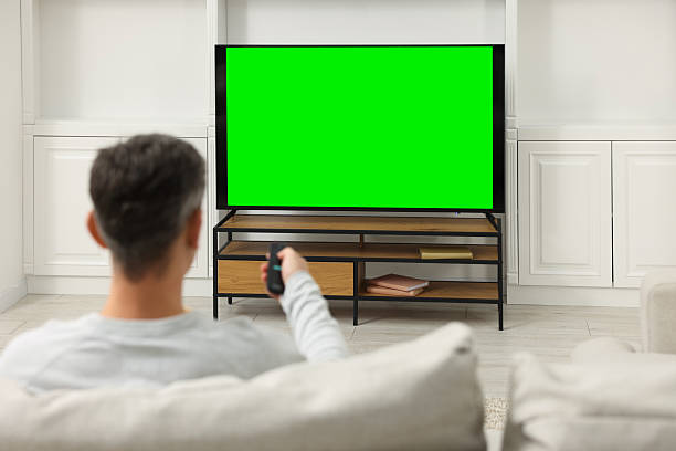 istock Man watching TV on sofa at home, back view 2213901581