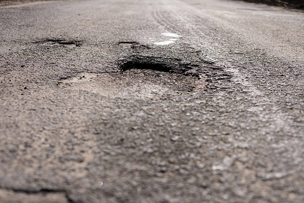 istock A neglected street features significant road damage with deep potholes and cracked asphalt, highlighting the need for repairs and maintenance 2213902139