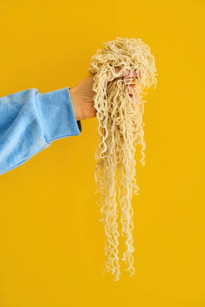Hand holding clump of long cooked ramen noodles