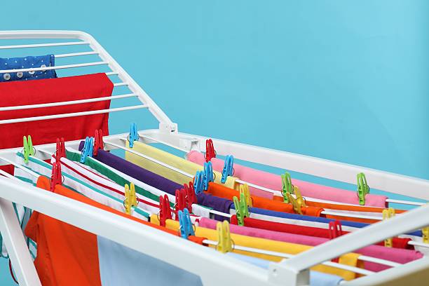 Drying rack with fresh clean laundry on light blue background, closeup