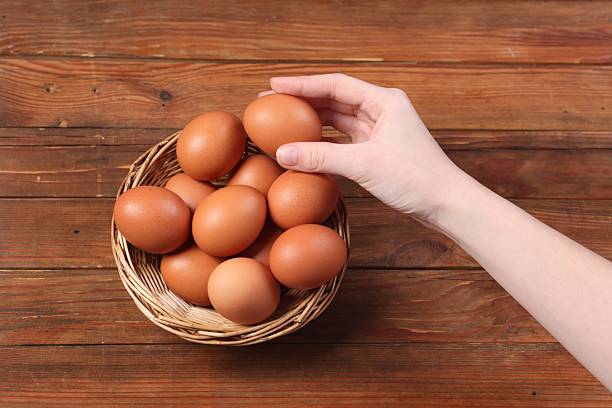 istock Woman with raw eggs at wooden table, top view 2213905572