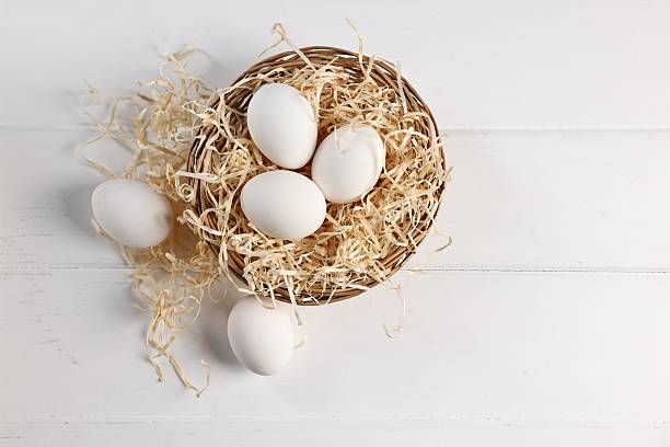 istock Raw eggs in basket on white wooden table, top view 2213906089