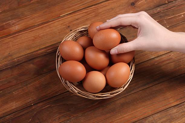 istock Woman with raw eggs at wooden table, closeup 2213906108