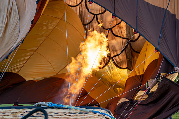 A hot air balloon with a fire burning inside of it. The fire is orange and yellow. The balloon is open and the fire is visible