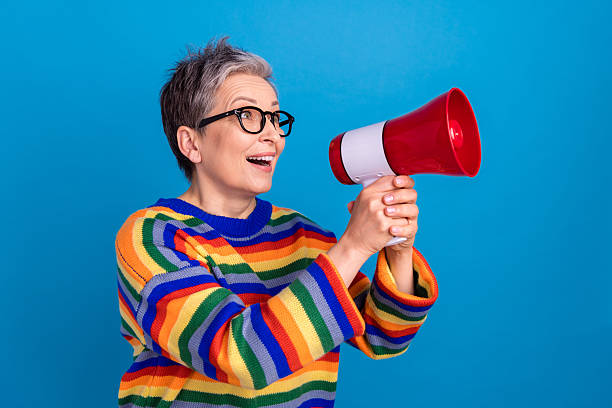 istock Profile portrait of positive aged lady hands hold loudspeaker communicate empty space isolated on blue color background 2213907577