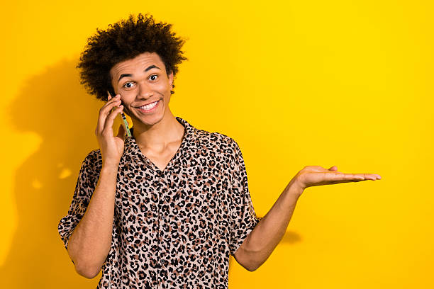 istock Photo of positive cheerful guy dressed leopard print shirt chatting modern device arm empty space isolated yellow color background 2213909005